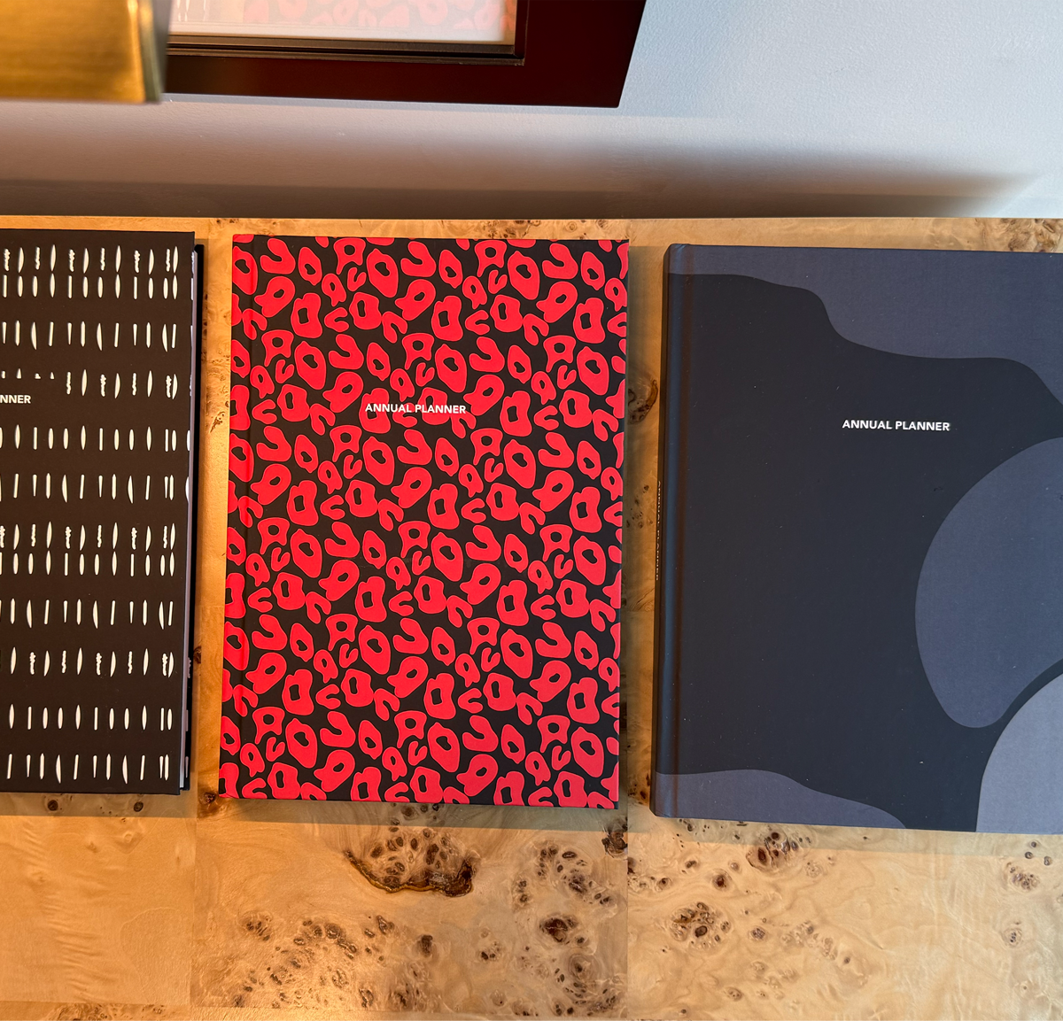 Three planners with different designs on a wooden surface