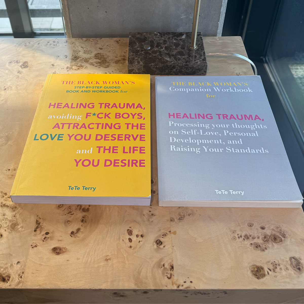 Two books by TeTe Terry on a wooden desk.