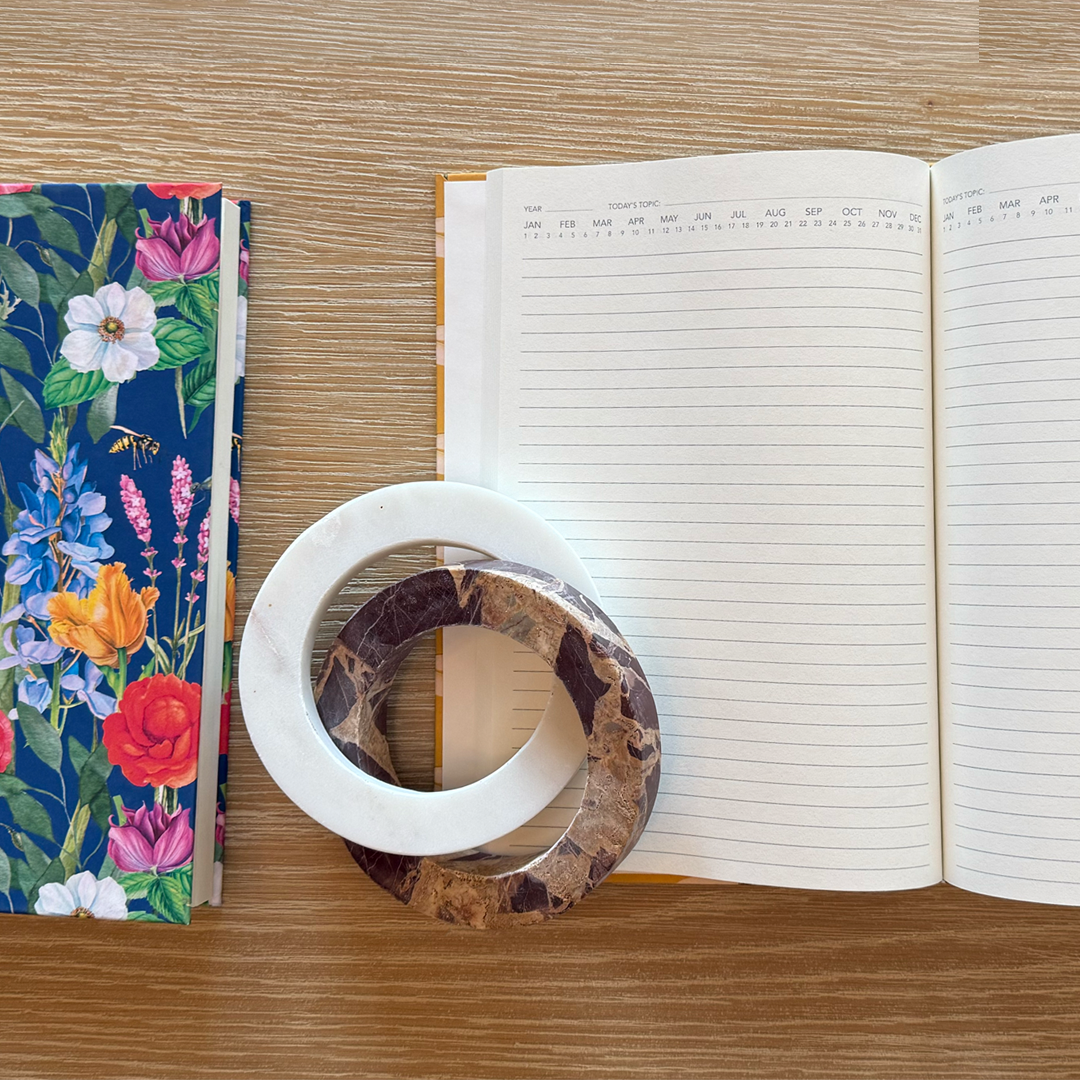 Open notebook with floral notebook and decorative ring on a wooden surface