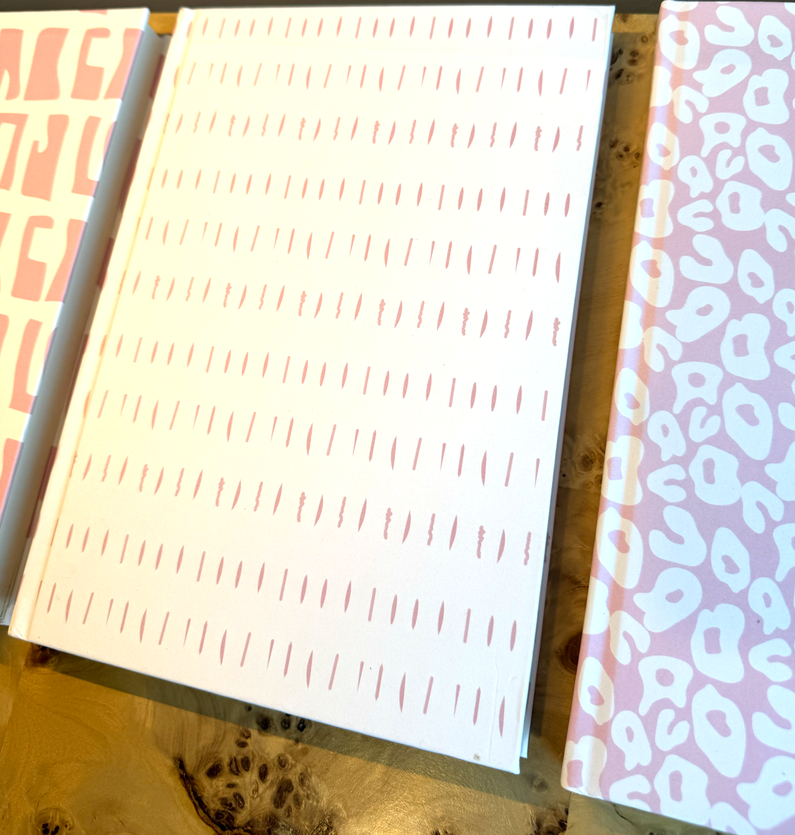 Pink and White Journals and Planners with different patterns on a desk