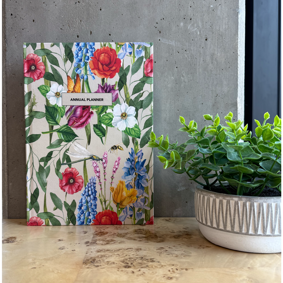 Floral planner on a wooden desk with a plant in the background
