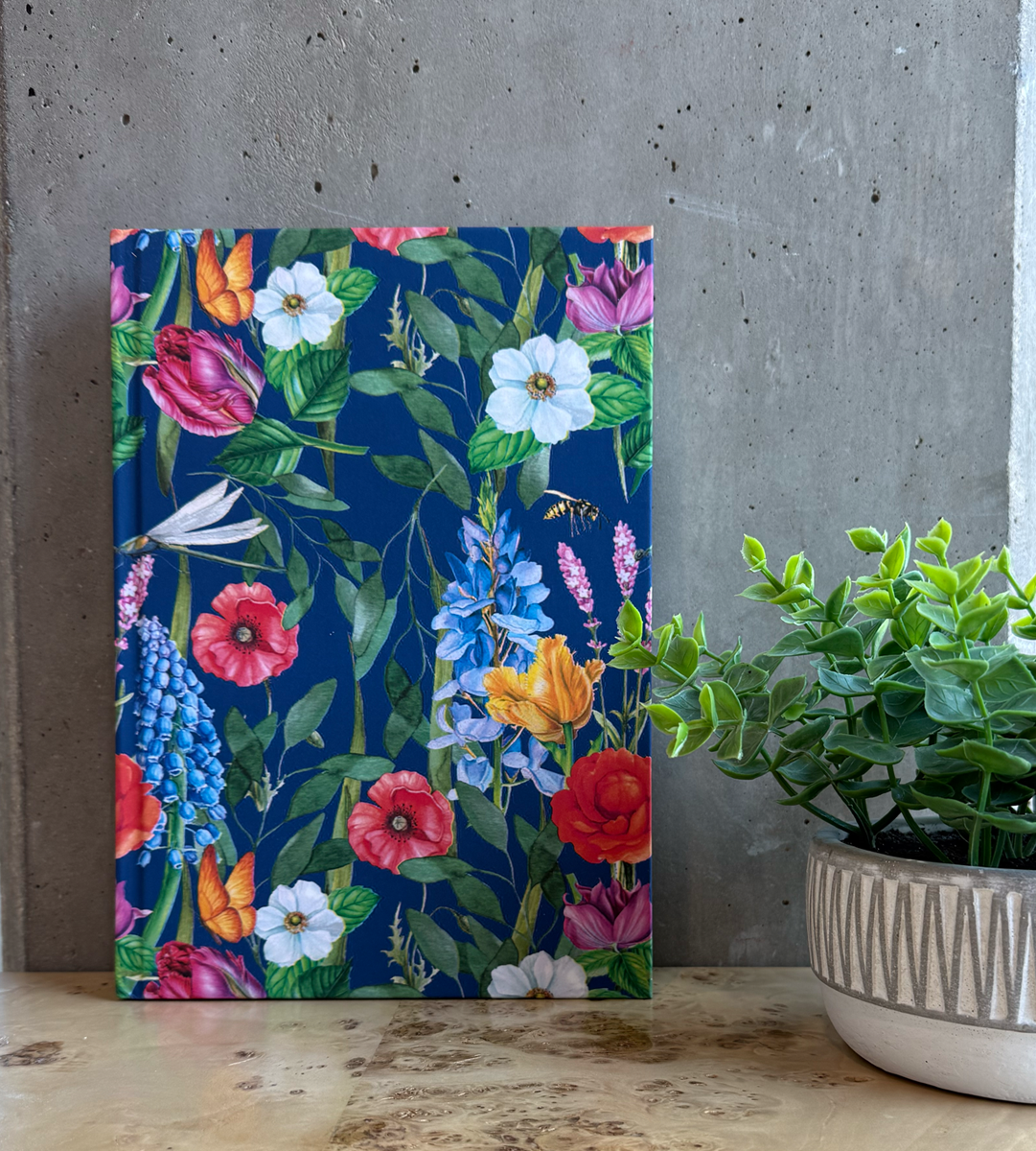 Floral-patterned journal on a wooden desk with a plant in the background