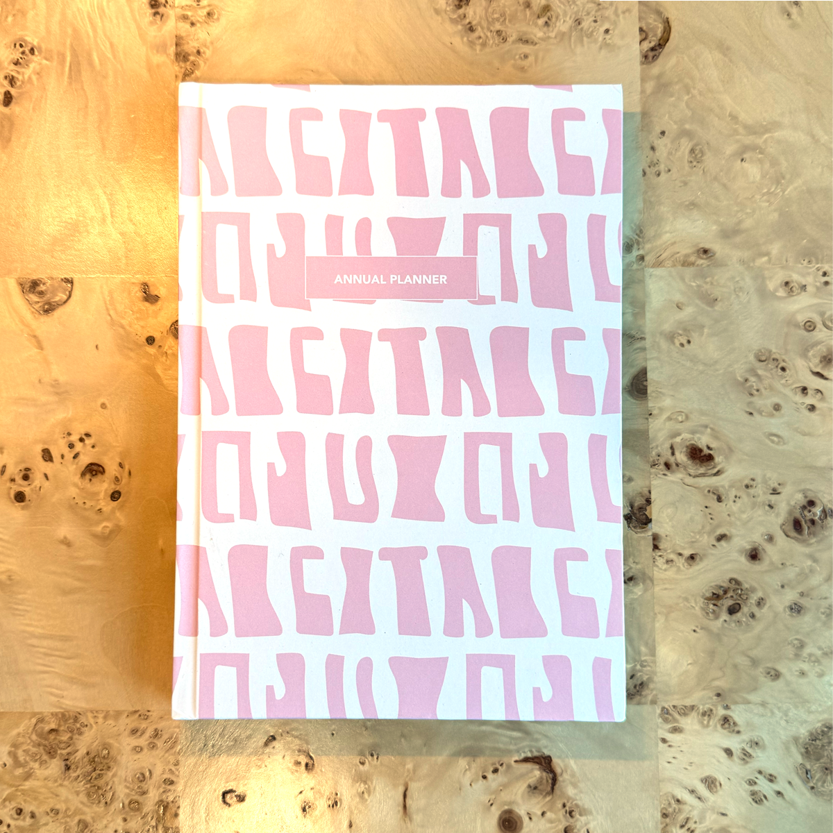 Planner with pink batik print design on a textured desk
