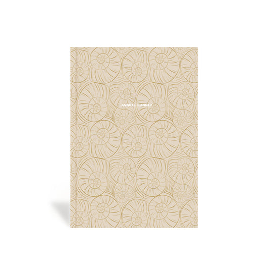 A beige, hardbound planner with a shell pattern on the cover.
